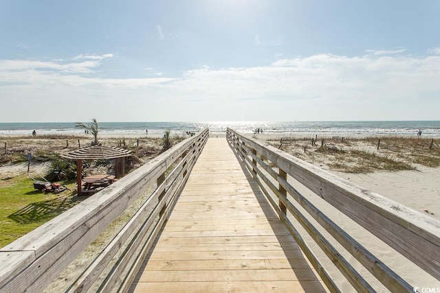 view of community with a gazebo, a water view, and a beach view