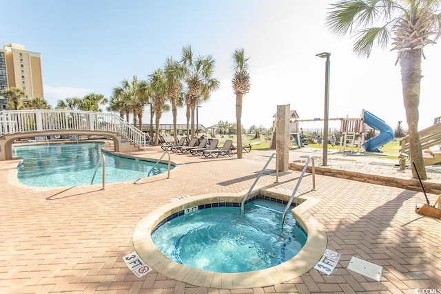 pool with a hot tub, a patio area, and playground community