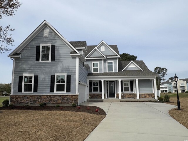 craftsman inspired home with a lawn, a porch, and a garage