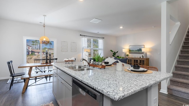 kitchen featuring a kitchen island with sink, stainless steel dishwasher, dark wood-type flooring, and hanging light fixtures