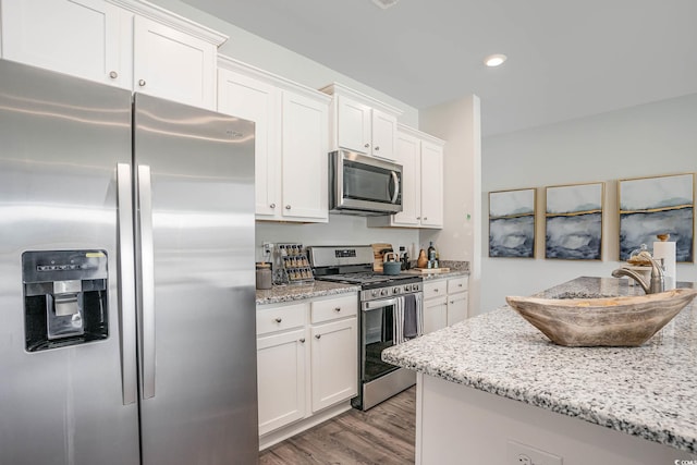 kitchen featuring appliances with stainless steel finishes, white cabinets, light stone countertops, and light hardwood / wood-style floors