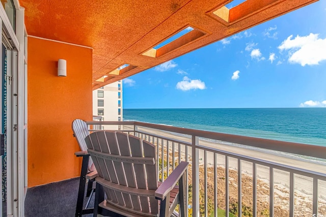 balcony with a water view and a view of the beach