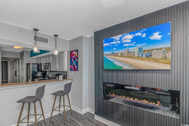5300 N Ocean Blvd Unit 1405, Myrtle Beach, SC 29577 - kitchen featuring a textured ceiling, visible vents, stainless steel appliances, baseboards, and dark wood-style flooring