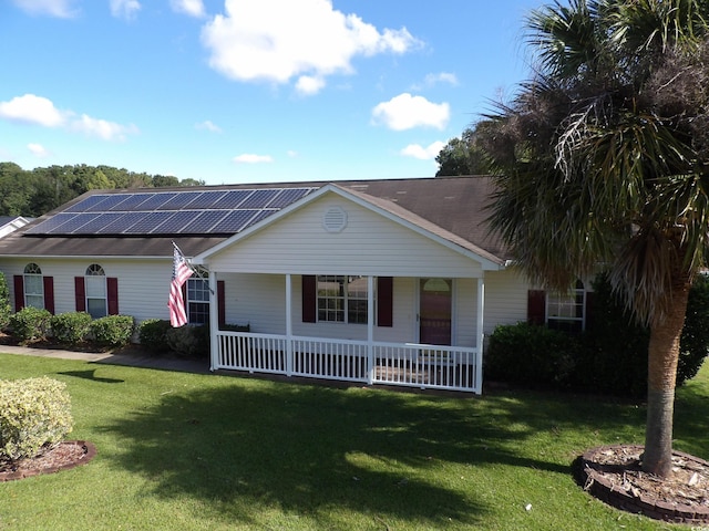 ranch-style home with covered porch, a front yard, and solar panels