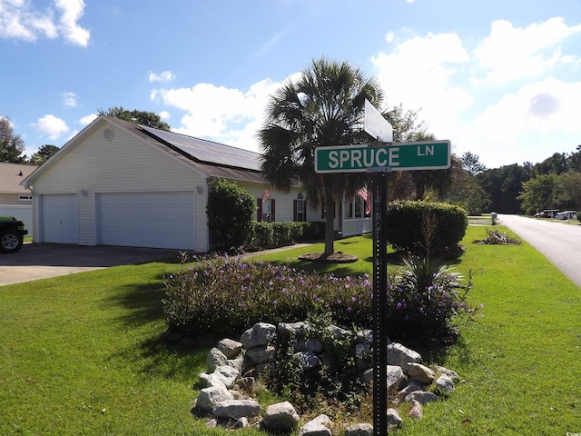 view of front facade with solar panels, a front yard, and a garage