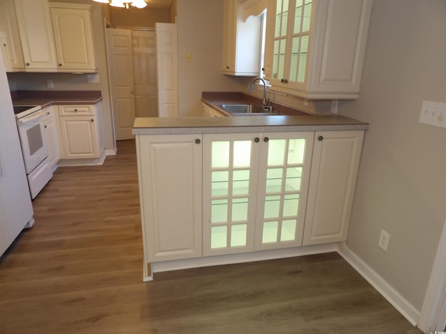 kitchen with dark wood-type flooring, kitchen peninsula, sink, white cabinets, and white stove