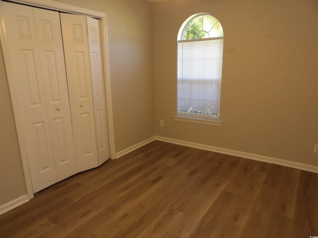 unfurnished bedroom with dark wood-type flooring and a closet