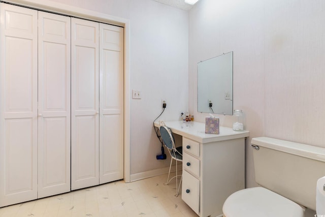 bathroom with toilet, baseboards, and a closet