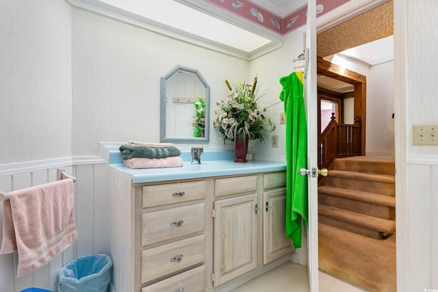 bathroom featuring wainscoting, vanity, a decorative wall, and wallpapered walls