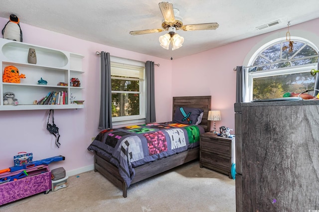 carpeted bedroom featuring multiple windows, a ceiling fan, baseboards, and a textured ceiling