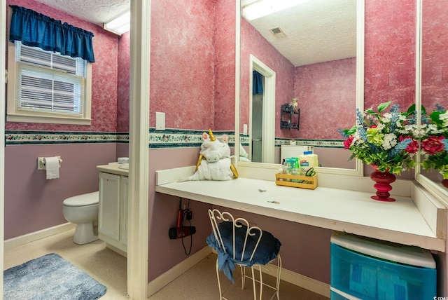 bathroom with vanity, toilet, a textured ceiling, and baseboards