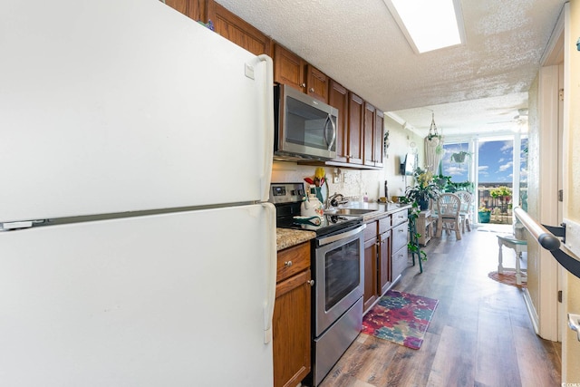 kitchen featuring dark wood-type flooring, backsplash, appliances with stainless steel finishes, and a textured ceiling