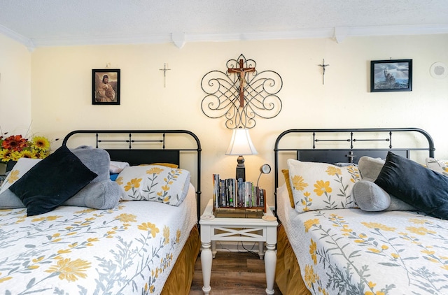 bedroom featuring ornamental molding, a textured ceiling, and wood-type flooring