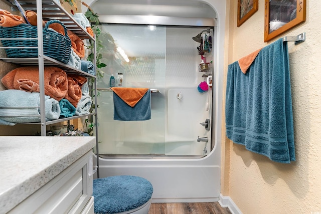 full bathroom with shower / bath combination with glass door, vanity, wood-type flooring, and toilet