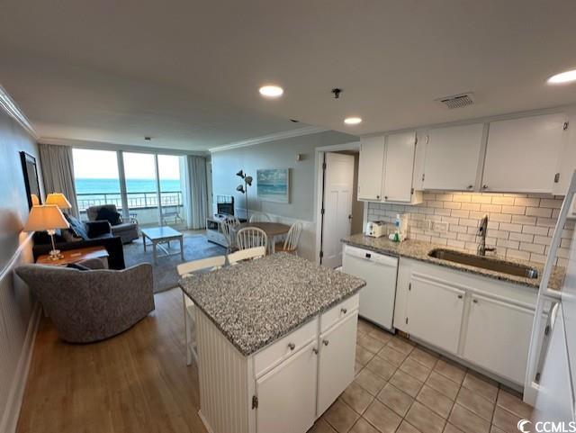 kitchen with a water view, white dishwasher, a center island, and white cabinets