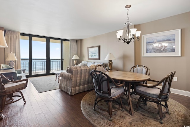 dining area with expansive windows, a water view, dark hardwood / wood-style floors, and an inviting chandelier