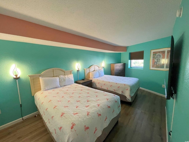 bedroom with a textured ceiling and dark hardwood / wood-style flooring