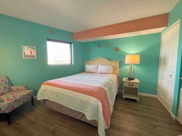 bedroom with dark wood-type flooring and a closet