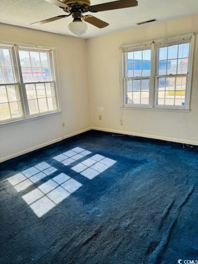 unfurnished room featuring a textured ceiling, ceiling fan, and dark colored carpet