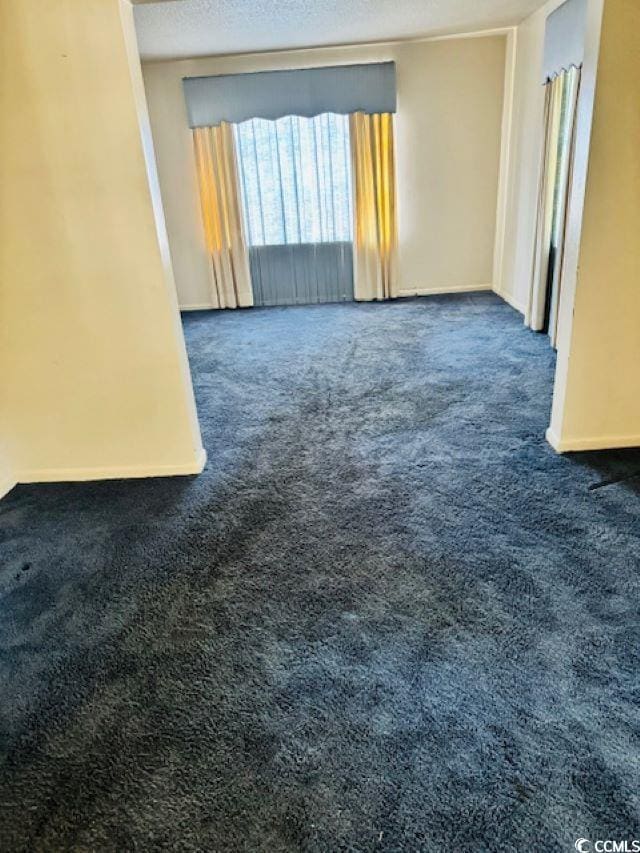 empty room featuring dark carpet and a textured ceiling