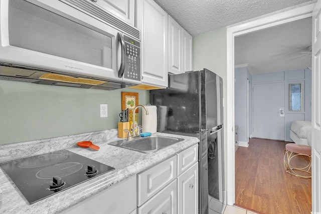 kitchen with white cabinetry, hardwood / wood-style flooring, a textured ceiling, black appliances, and sink