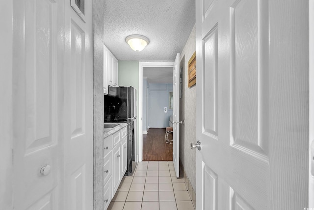 corridor featuring a textured ceiling and light tile patterned flooring