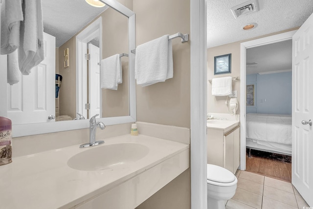 bathroom featuring vanity, a textured ceiling, toilet, and tile patterned flooring