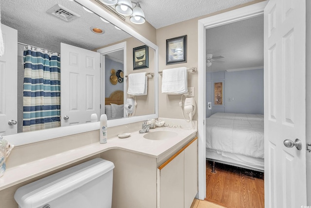 bathroom featuring a textured ceiling, ceiling fan, toilet, vanity, and hardwood / wood-style flooring