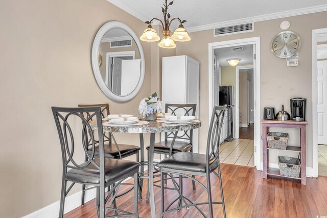 dining area featuring hardwood / wood-style floors, a notable chandelier, and crown molding