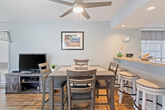 dining space with ceiling fan, a textured ceiling, and hardwood / wood-style floors