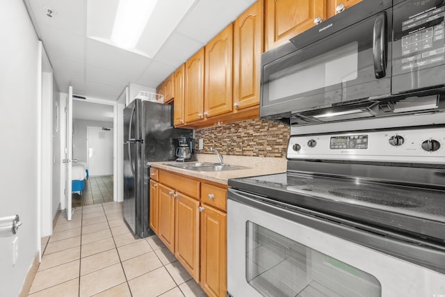 kitchen featuring black appliances, sink, a paneled ceiling, decorative backsplash, and light tile patterned floors