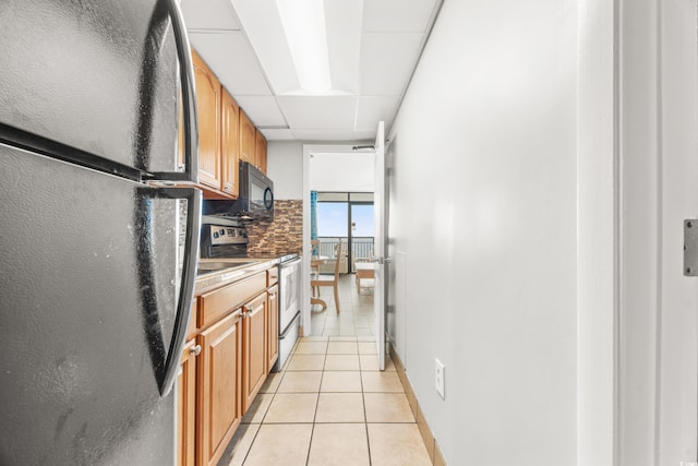 kitchen with a paneled ceiling, appliances with stainless steel finishes, and light tile patterned floors