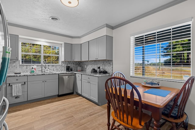 kitchen featuring light stone countertops, stainless steel dishwasher, ornamental molding, light hardwood / wood-style floors, and sink