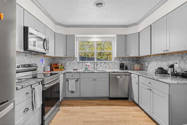 kitchen featuring sink, appliances with stainless steel finishes, light hardwood / wood-style flooring, and crown molding