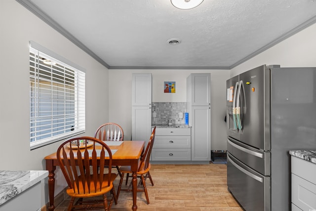 dining area featuring ornamental molding, a textured ceiling, and light wood-type flooring