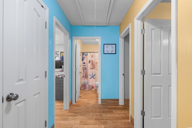 corridor featuring a textured ceiling and light wood-type flooring