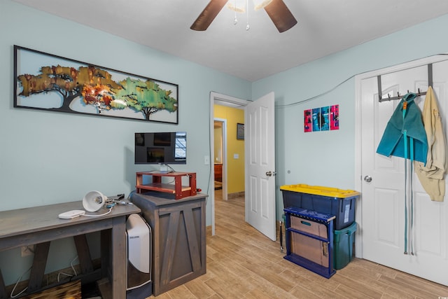 home office with light wood-type flooring and ceiling fan