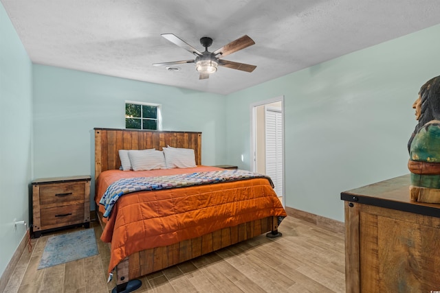 bedroom featuring light hardwood / wood-style floors, a textured ceiling, and ceiling fan