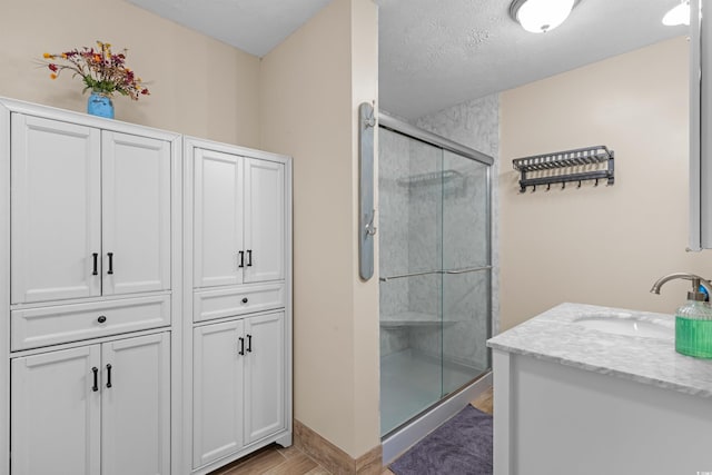 bathroom featuring a shower with door, vanity, a textured ceiling, and hardwood / wood-style flooring