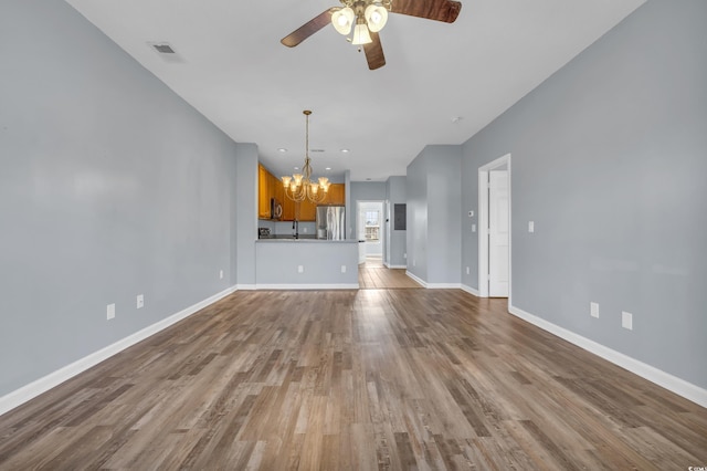 unfurnished living room with ceiling fan with notable chandelier, light wood-type flooring, and sink