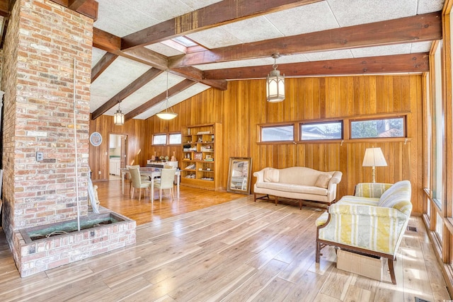 living room with light hardwood / wood-style floors, lofted ceiling with beams, and wooden walls