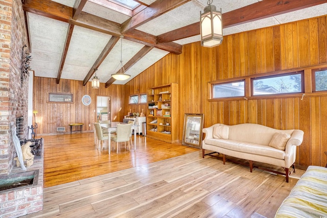 living room with wooden walls, light wood-type flooring, and lofted ceiling with skylight