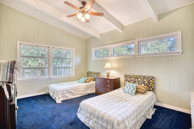 bedroom featuring wood walls, dark colored carpet, multiple windows, and ceiling fan