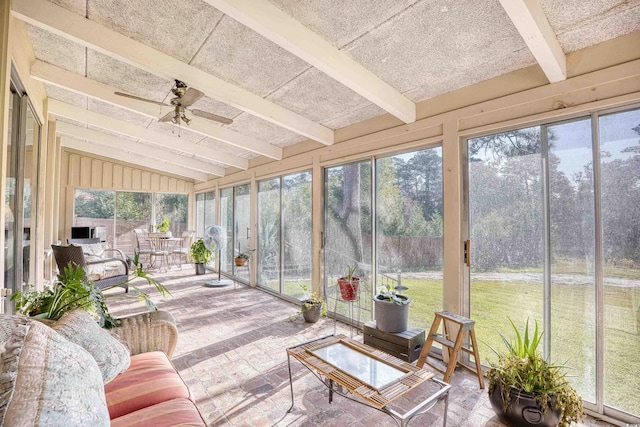 sunroom / solarium featuring ceiling fan, a healthy amount of sunlight, and vaulted ceiling with beams