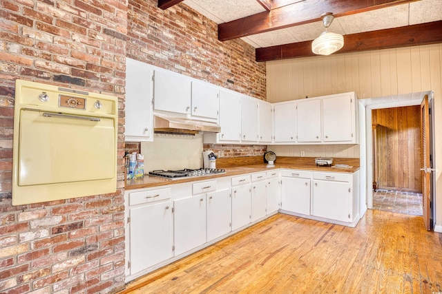 kitchen featuring white cabinetry, brick wall, beamed ceiling, and light hardwood / wood-style flooring