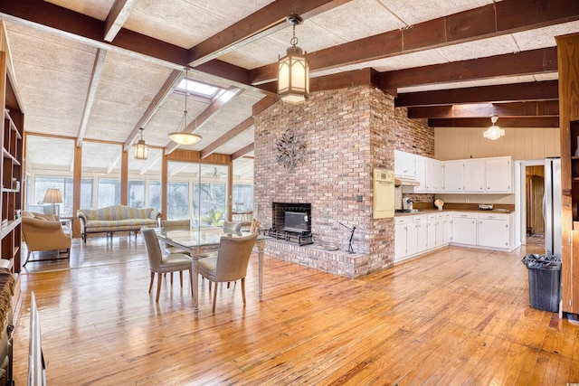 dining room featuring lofted ceiling with beams, light wood-type flooring, and a wood stove