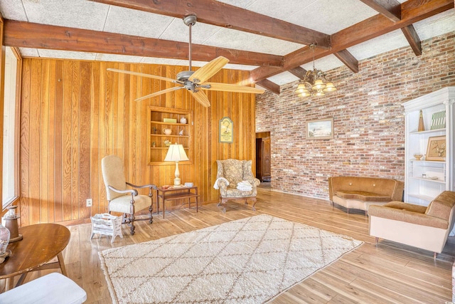 unfurnished room with hardwood / wood-style floors, ceiling fan with notable chandelier, lofted ceiling with beams, wooden walls, and brick wall