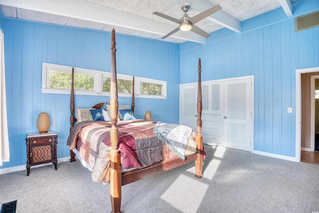 bedroom with wood walls, beamed ceiling, and ceiling fan