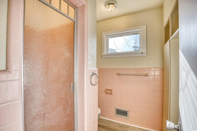 bathroom with toilet, hardwood / wood-style flooring, walk in shower, and tile walls