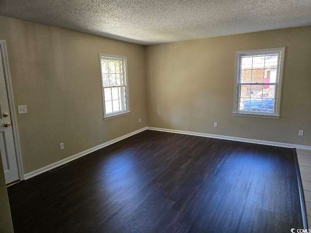 empty room featuring dark hardwood / wood-style floors and a textured ceiling